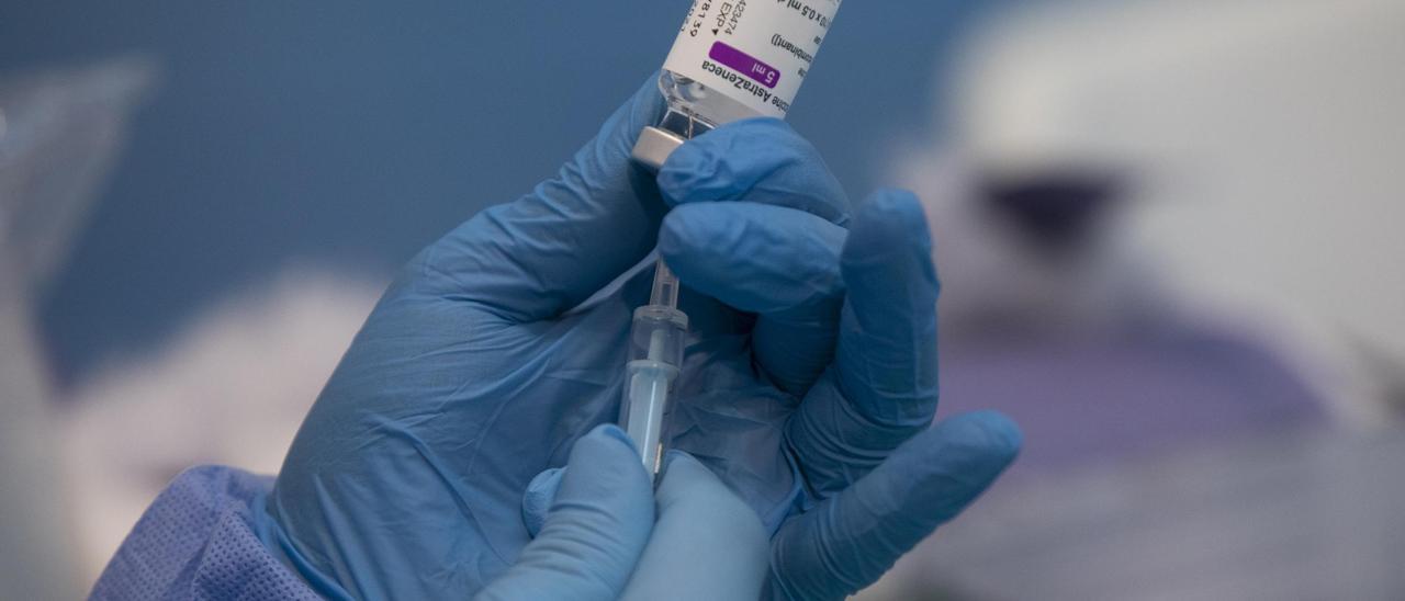 Una profesional sanitaria sostiene una jeringuilla con un vial de la vacuna contra la COVID-19 de AstraZeneca en un dispositivo de vacunación en el pabellón SADUS en Sevilla.
