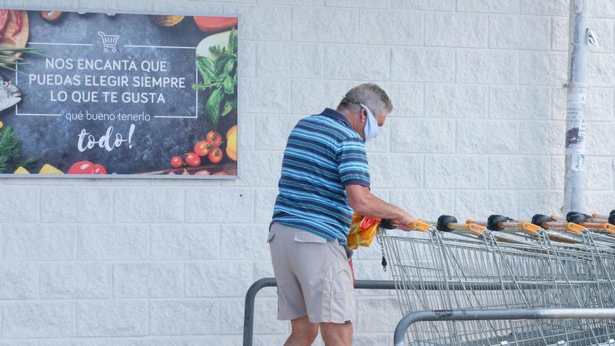 Un hombre coge un carro para comprar en un supermercado.