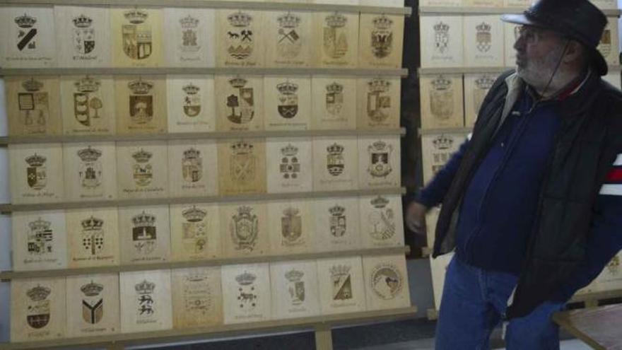 El artista Agustín Gonzalo ante un expositor de escudos de municipios de España y Portugal.