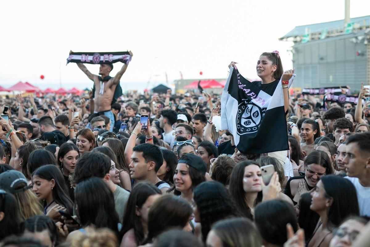 Una joven muestra una bandera de Dellafuente y, al fondo, un joven una bufanda del artista, durante su concierto en el Share Festival