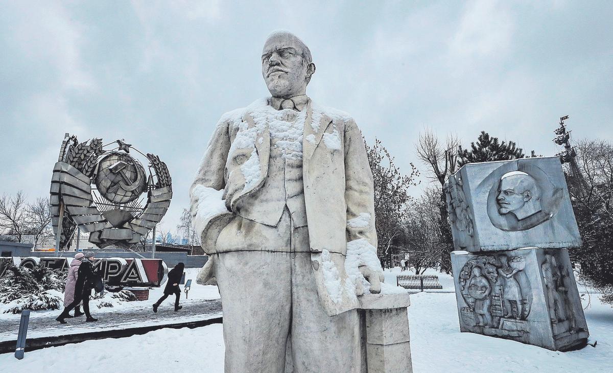 Varias personas caminan junto a una estatua de Vladimir Ulyanov 'Lenin' y otros monumentos de la URSS en un parque de Moscú.