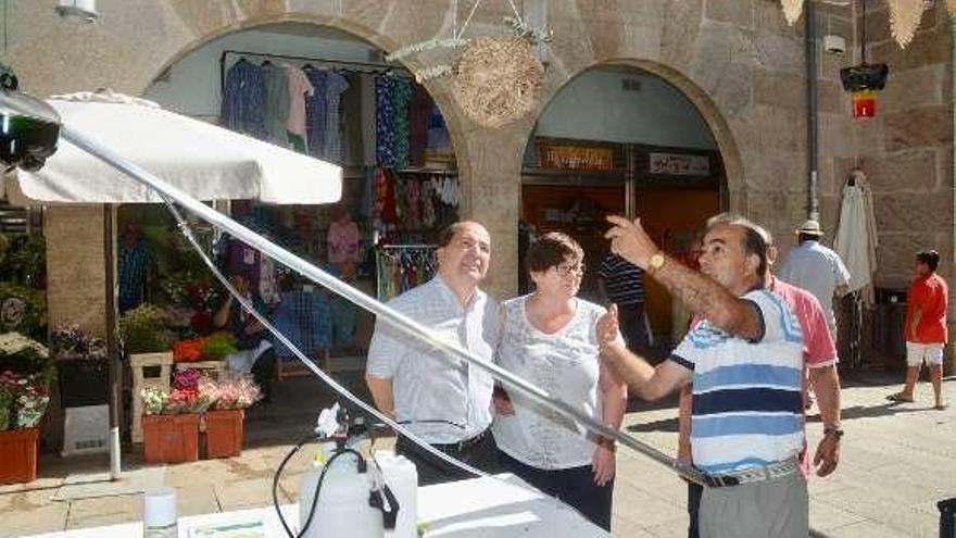 Arriba, una familia se interesa por los productos de la miel en la carpa, donde también se muestra (foto inferior) un nido de velutina. // R. Vázquez