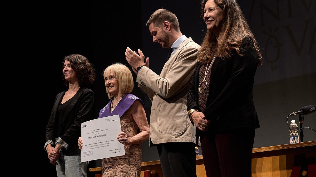 Una alumna exhibe cel diploma ante el alcalde y las representantes de la UV