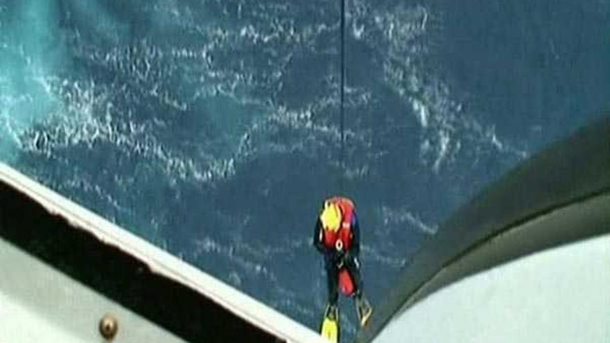 Un miembro de los equipos de rescate se descuelga al mar del helicóptero ``Pesca I´´.