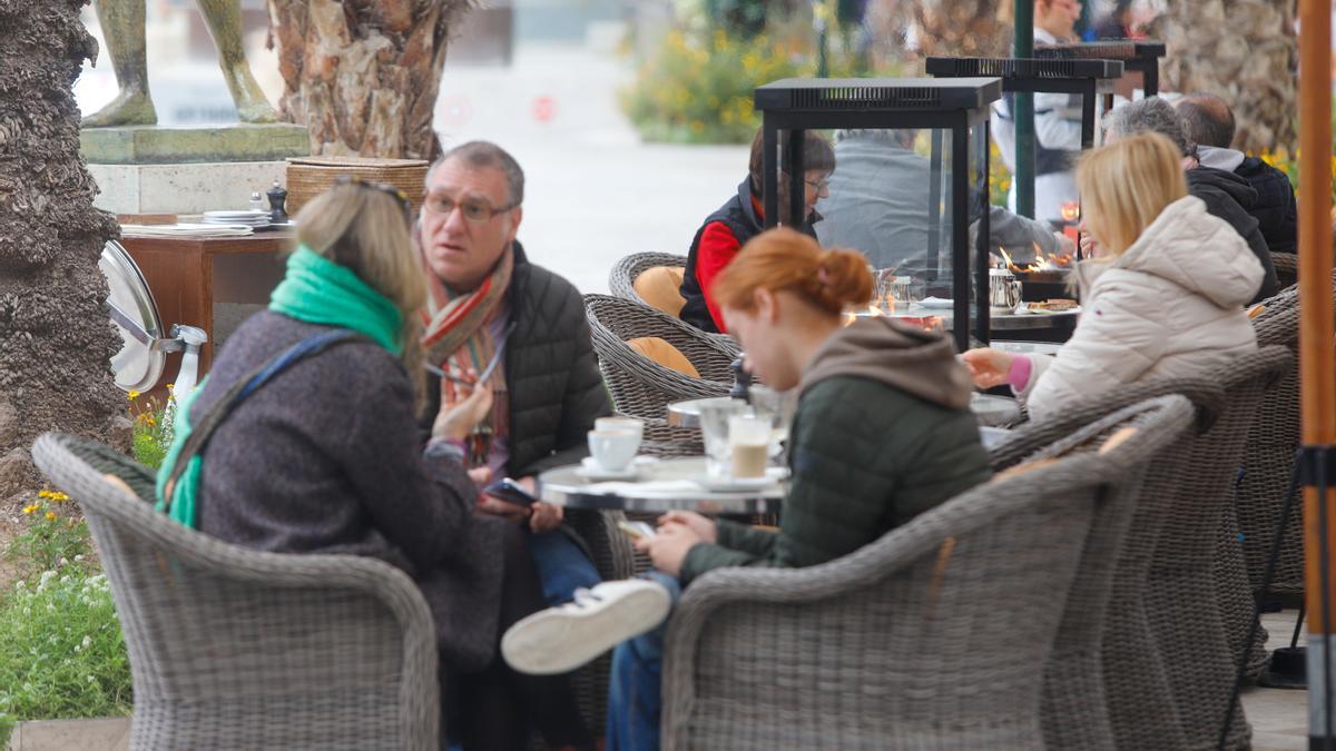 Turistas consumiendo varios cafés en una terraza del centro de València.