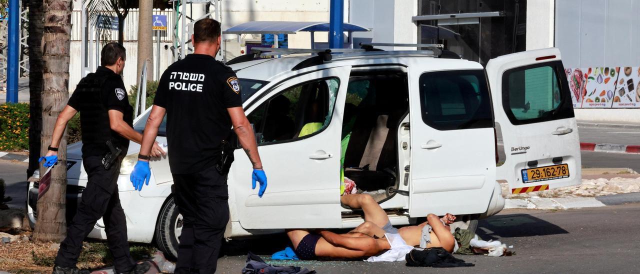 Dos policías junto a los cuerpos de dos de los asesinados por Hamas el sábado en Israel.