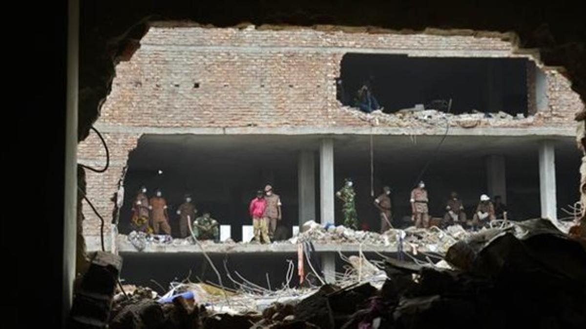 Miembros de los equipos de rescate observan los restos del edificio hundido en Savar, cerca de Dacca, este miércoles.