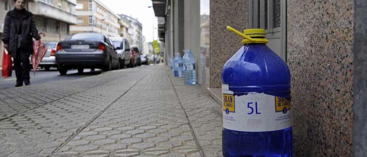 Las garrafas de agua, ayer, en la calle B de Lalín, alineadas sobre la acera. // Bernabé/Javier Lalín