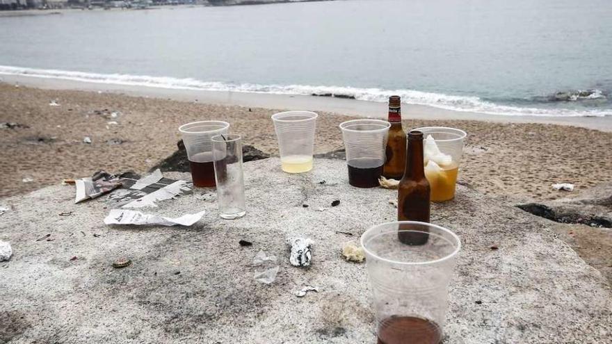 Vasos con restos de bebidas y botellas de cervezas después de la noche de San Juan en el Orzán.