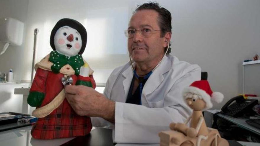 El pediatra Antonio Redondo en su consulta, junto a unos muñecos navideños.