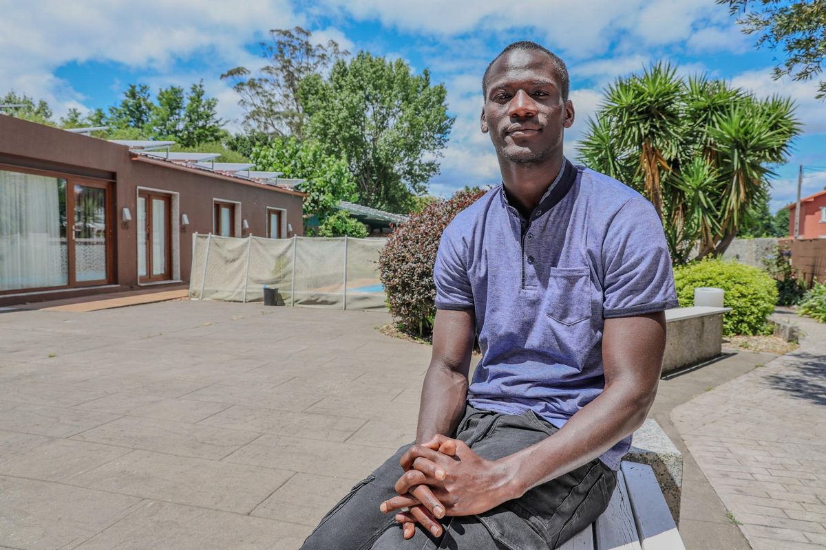 Djiby posa en uno de los bancos del hotel en el que reside