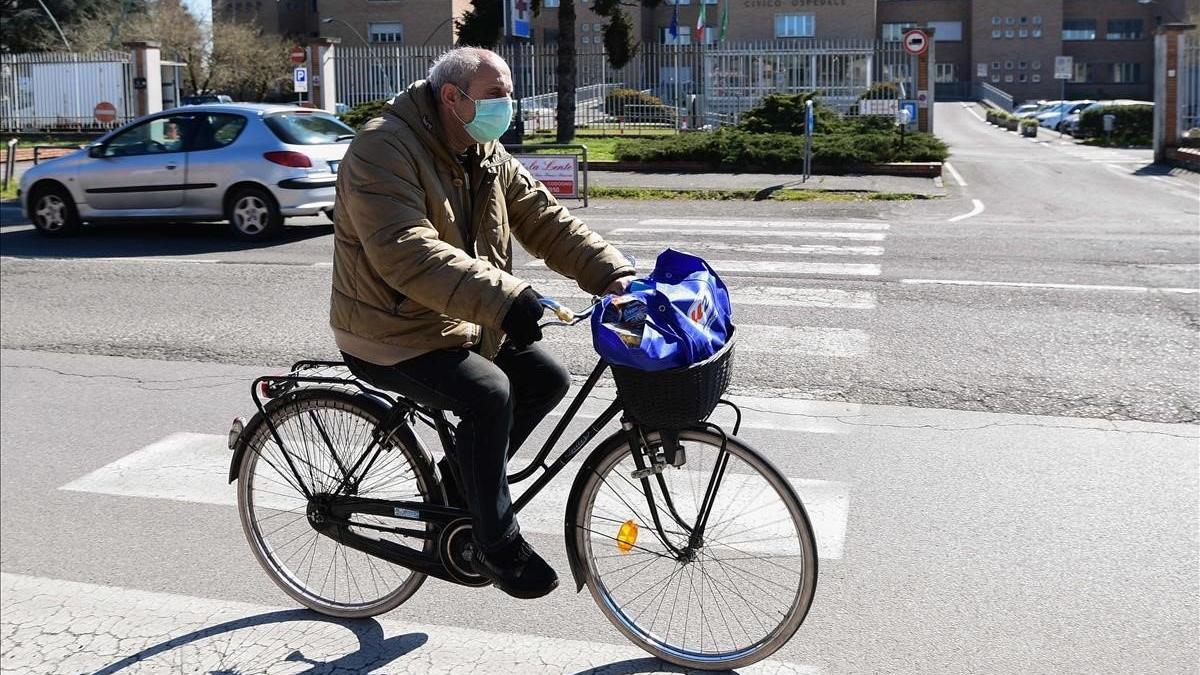 Un hombre con mascarilla pasa con su bicicleta junto al hospital de Codogno, en Milán.