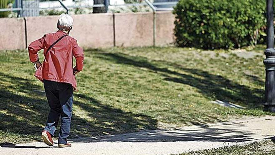 Una mujer mayor paseando por un parque.