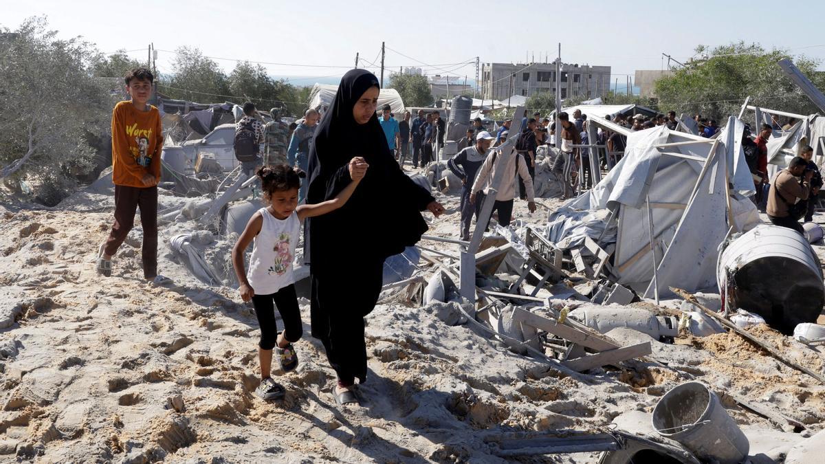 Palestinos inspeccionan los daños en el lugar de un ataque israelí a un campamento de tiendas que alberga a personas desplazadas, en Khan Younis, al sur de la Franja de Gaza.