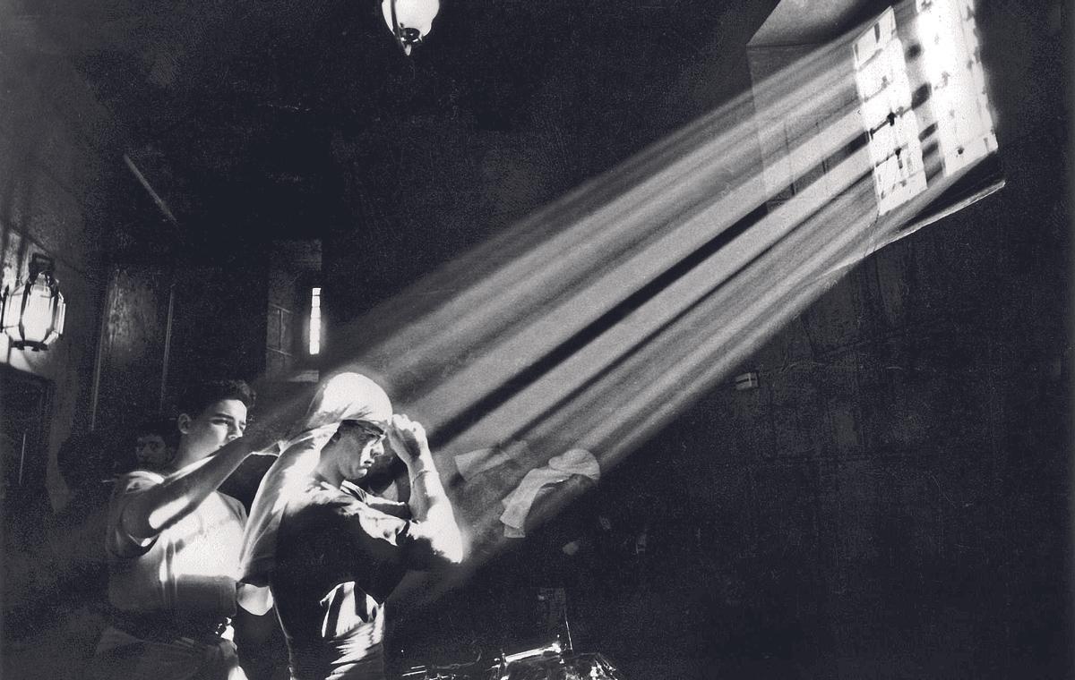 Un grupo de hermanos costaleros se colocan el costal en el interior de la iglesia de San Nicolás.