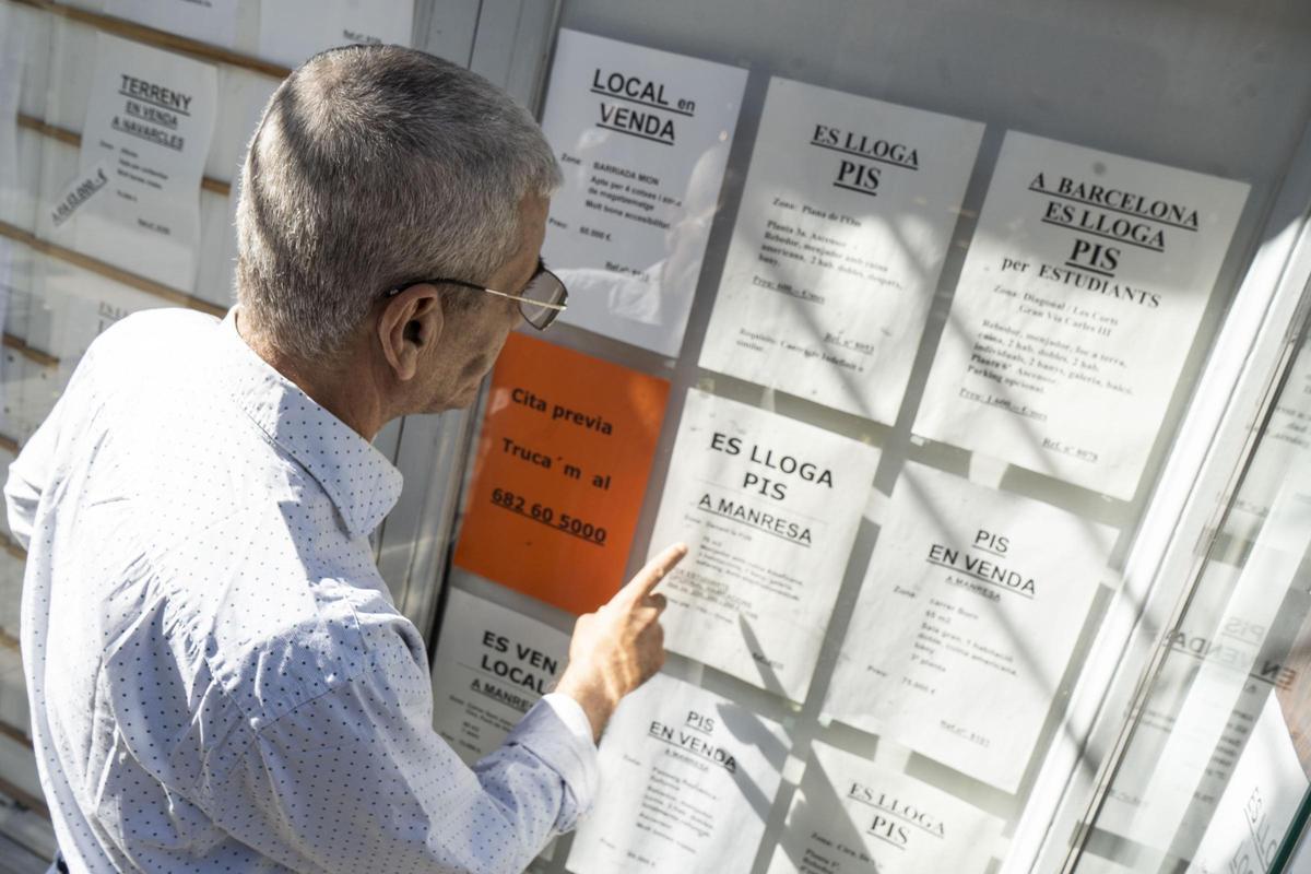 Una persona consultant els lloguers anunciats a l'aparador d'una immobiliària