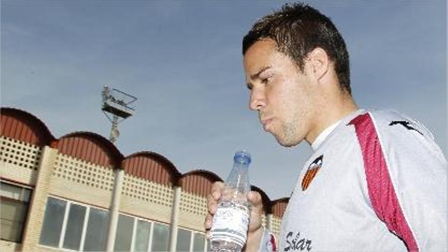 Bernat apura una botella de agua, con el edificio de la ciudad deportiva al fondo.