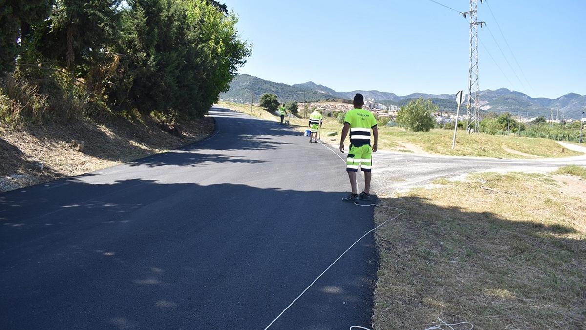 Varios operarios terminan de pintar la señalización vial en el camino de San Joaquín.