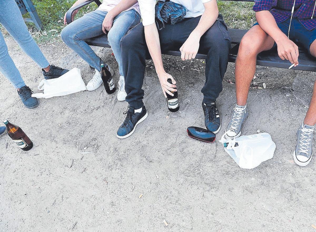 Un grup de joves amb cerveses en un banc, en una imatge d'arxiu.