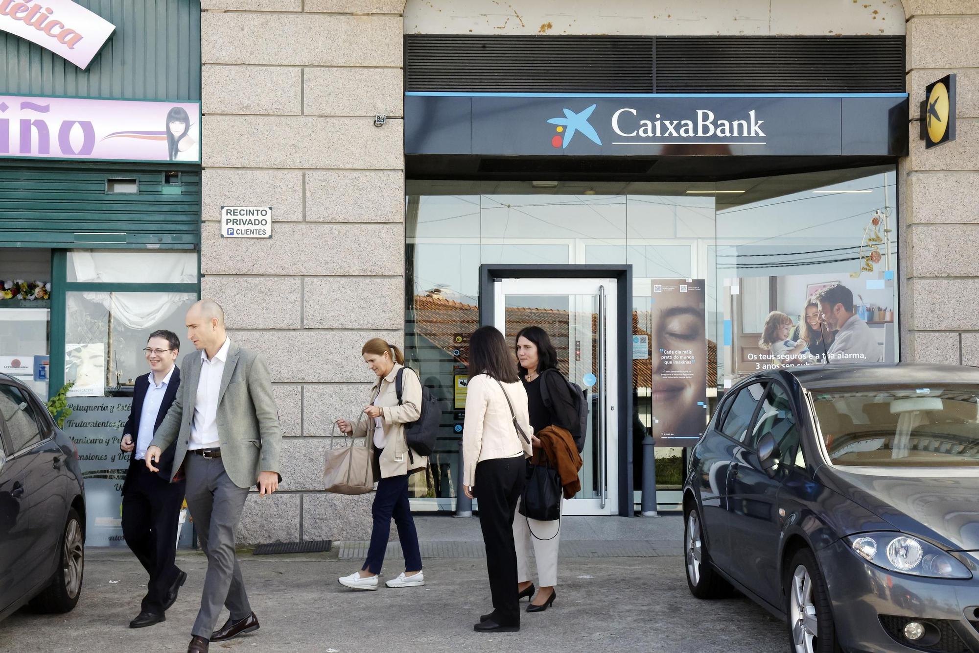 Empleados de CaixaBank saliendo este mediodía de la sucursal atracada en Beade