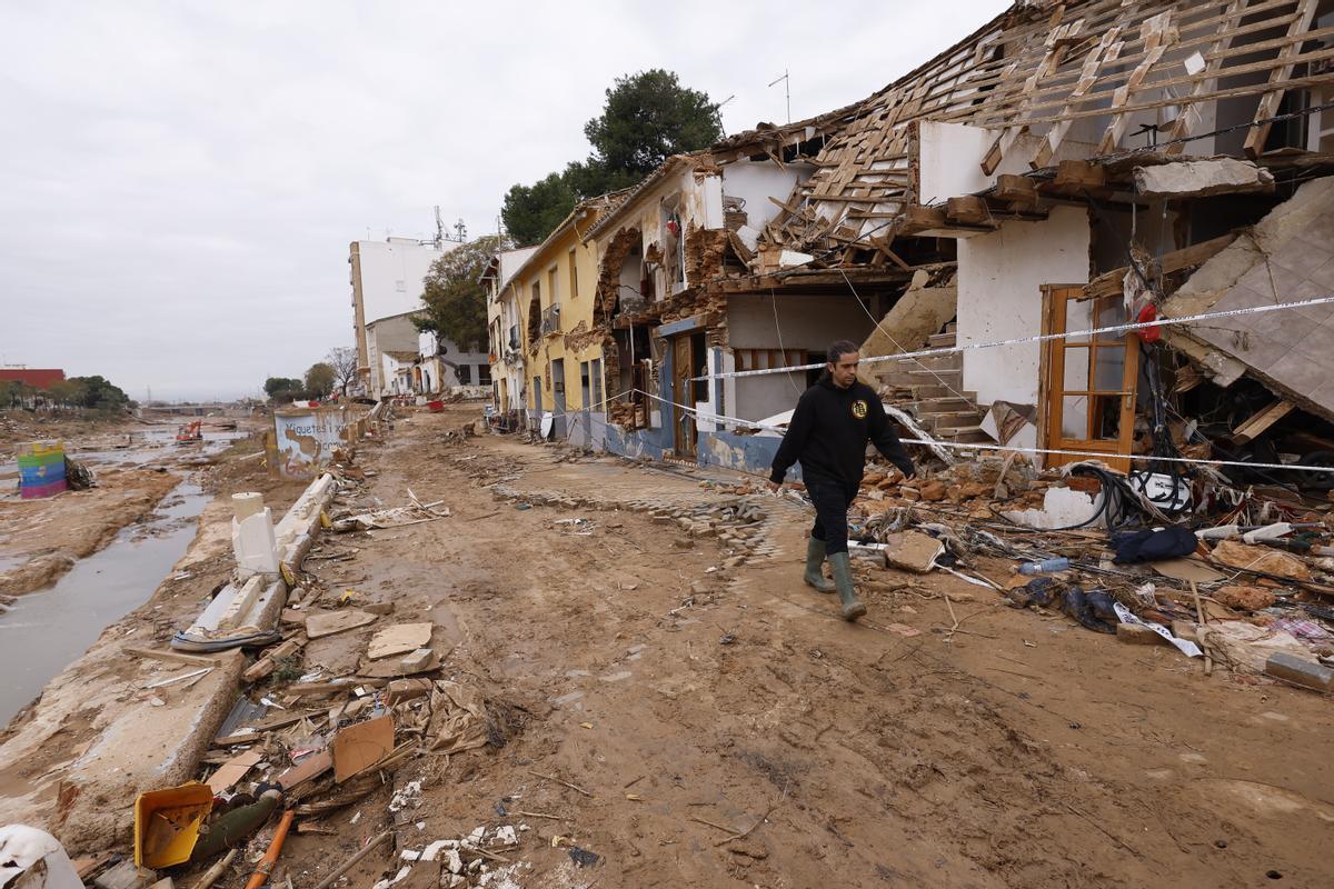 Una vecina pasa junto a las casas destrozadas en Barranco del Poyo, en Picanya (Valencia).