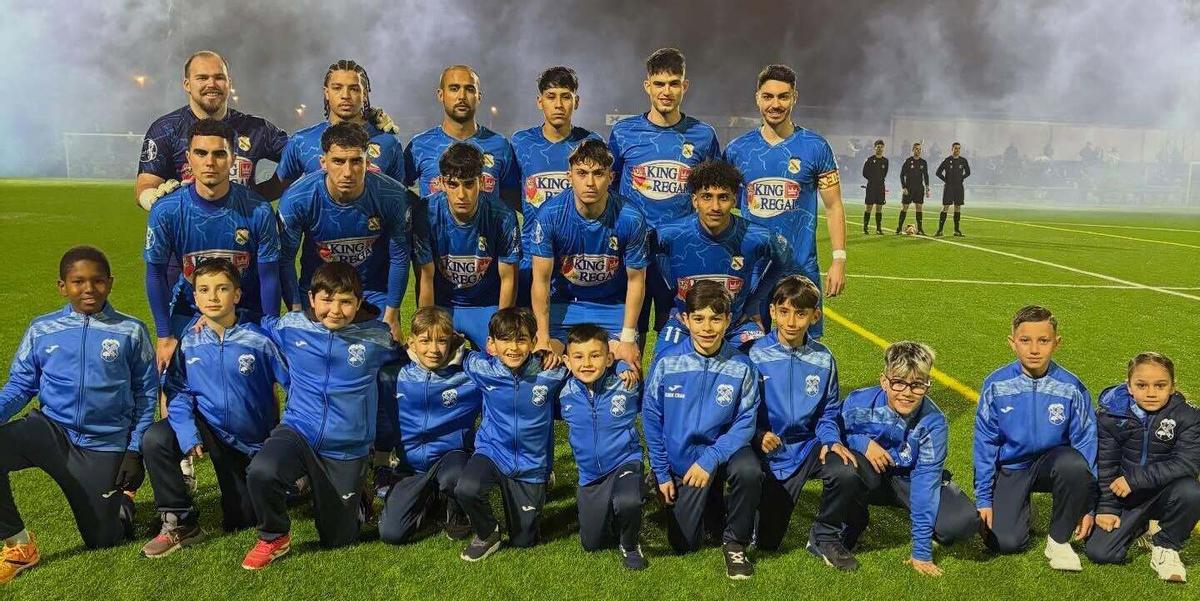 El primer equipo olivense posa con uno de la base antes del encuentro copero