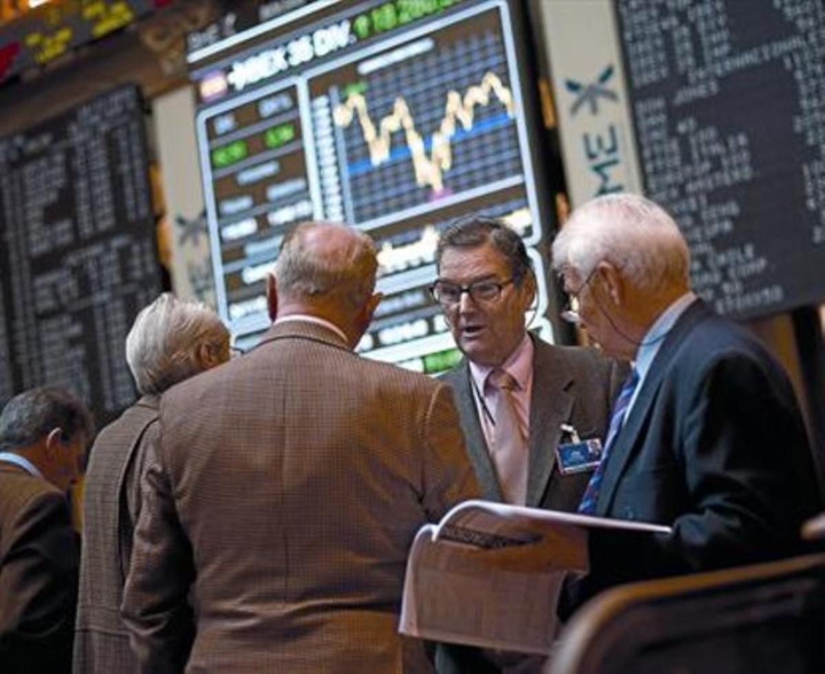 Uns inversors conversen davant un dels panells dela Borsa de Madrid, ahir.