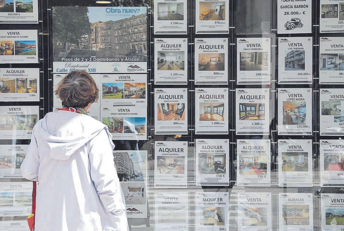 Una mujer observa anuncios de viviendas en una inmobiliaria de Vigo. |   // ALBA VILLAR