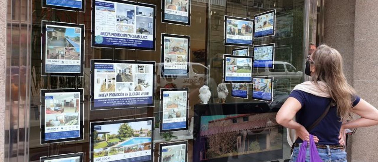 Una mujer ve el escaparate de una inmobiliaria.