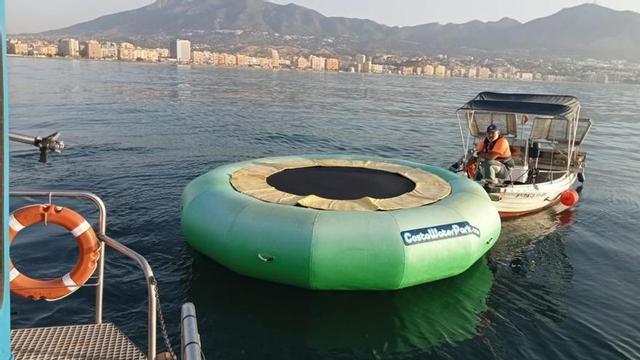Un operario retira un flotador de plástico en una playa de la Costa.