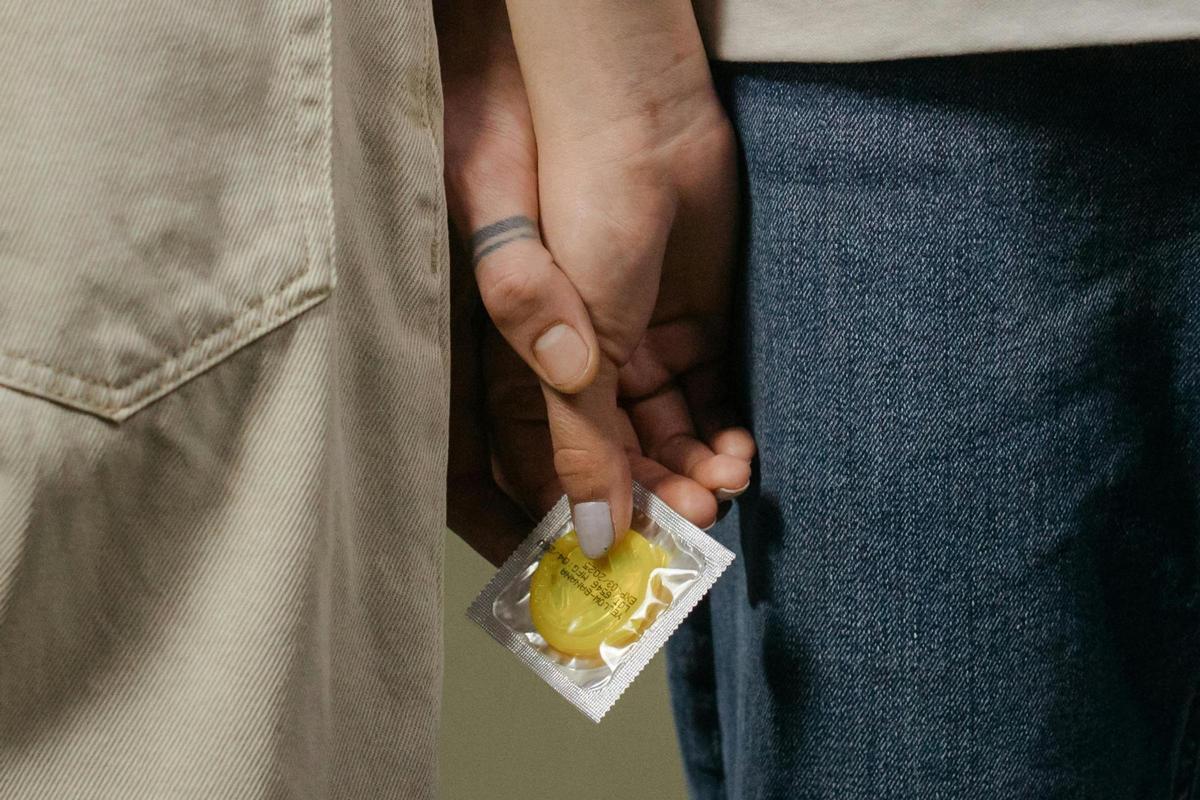 Dos personas con un preservativo en la mano