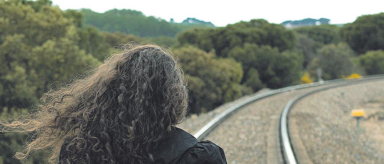 Una mujer caminando por una vía del tren.