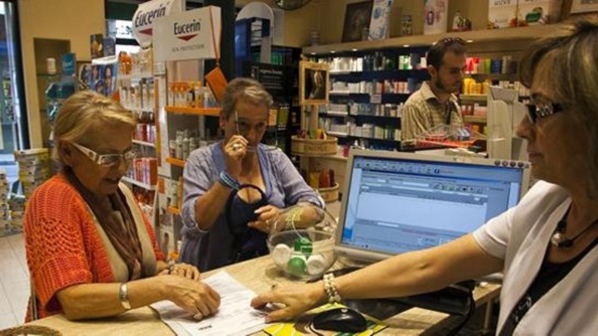 Una clientas recogen sus medicamentos con receta en una farmacia barcelonesa.