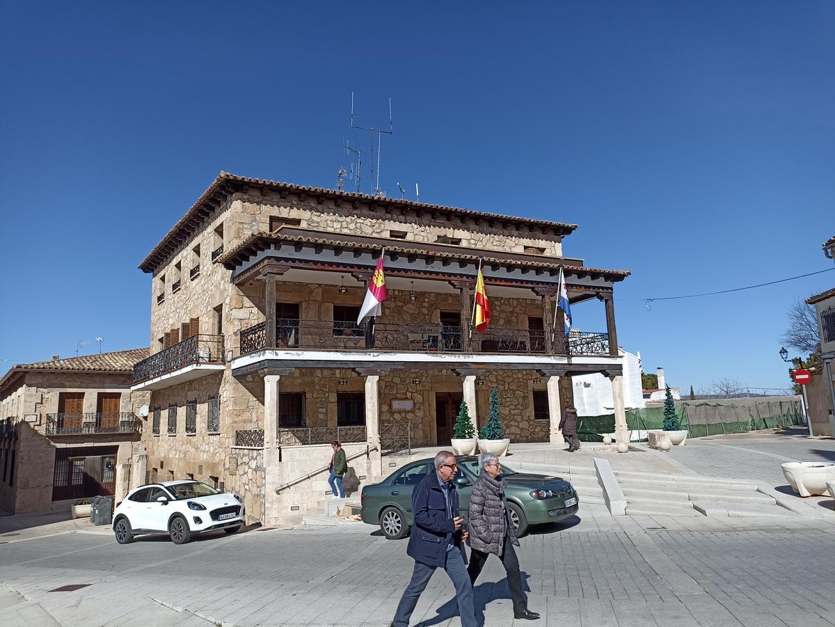 Dos personas pasan frente al Ayuntamiento de Almonacid de Zorita.