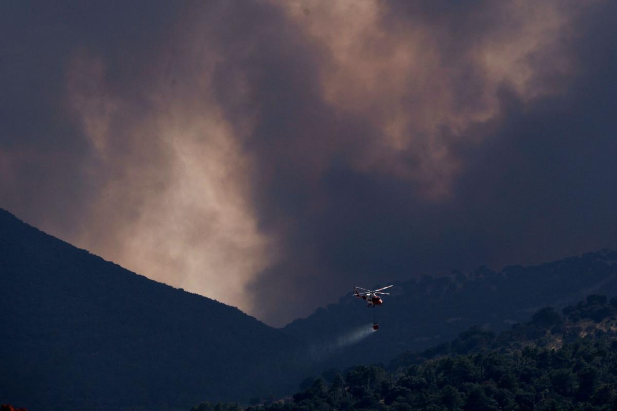 Un helicóptero de extinción de incendios arroja agua sobre un incendio forestal cerca de Robledo de Chavela, a unos 60 kilómetros al oeste de Madrid, el 27 de julio de 2026.