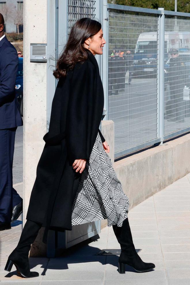 La reina Letizia con abrigo negro de Carolina Herrera, vestido con estampado príncipe de Gales de Pedro del Hierro y botas de tacón cómodo en Alicante