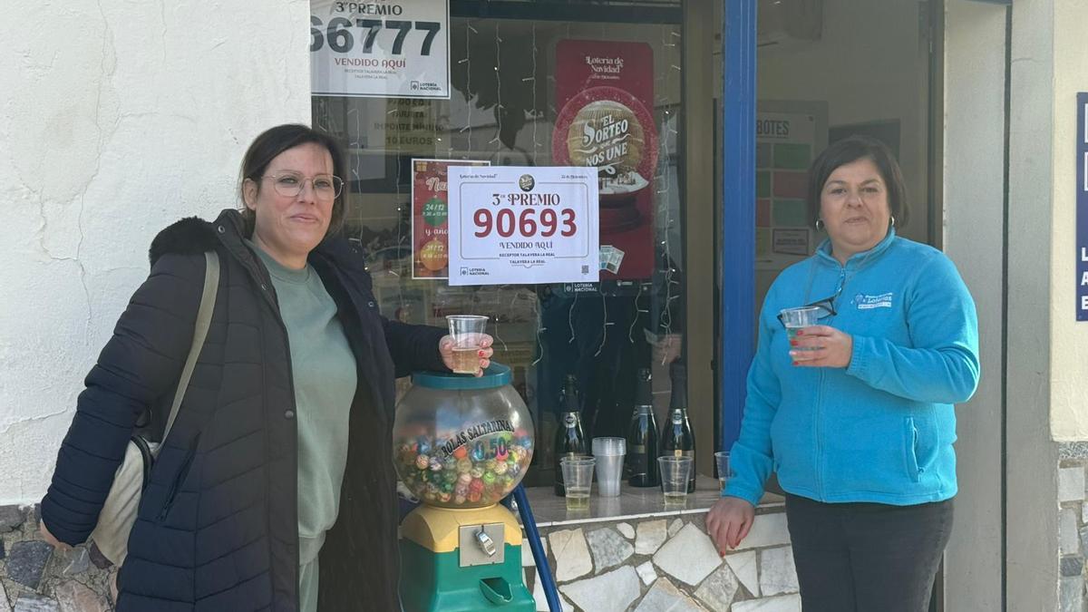 Pepi Rey, a la izquierda, celebra el tercer premio repartido en su establecimiento con una vecina de Talavera la Real (Badajoz).