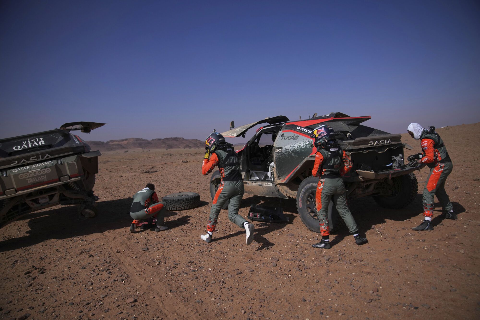 Driver Nasser Al-Attiya, right, and co-driver Edouard Boulanger are helped by driver Cristina Gutierrez and co-driver Pablo Moreno during the fourth stage of the Dakar Rally between Al Henakiyah and Alula, Saudi Arabia, Wednesday, Jan. 8, 2025. (AP Photo/Christophe Ena)