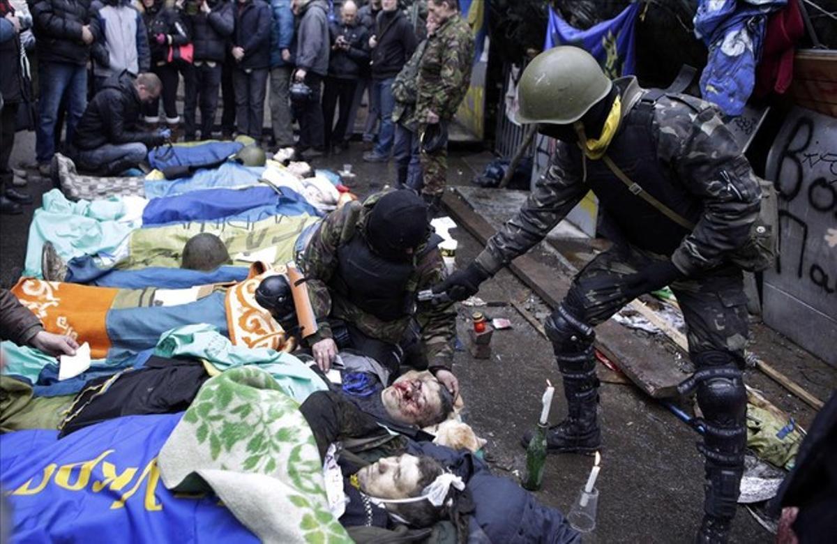Los cadáveres yacen en el suelo durante los enfrentamientos con la policía antidisturbios en el centro de Kiev.