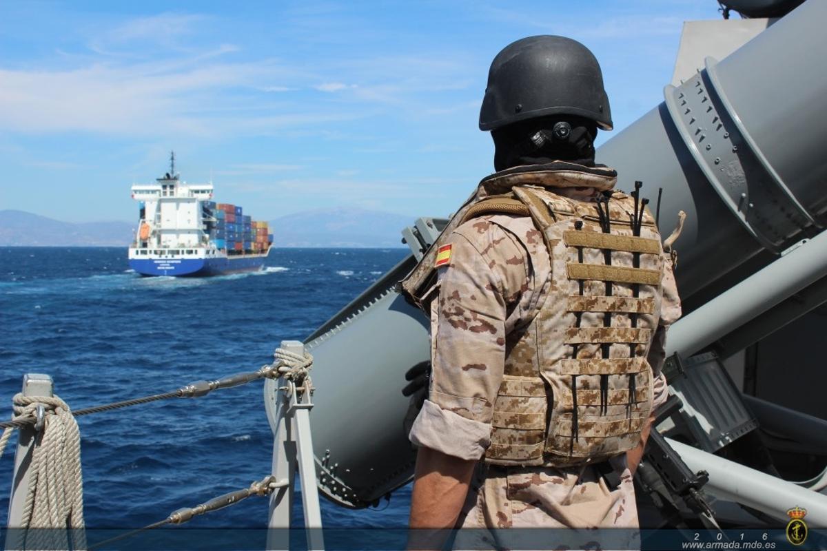 Un miembro de la unidad de seguridad de la fragata Méndez Núñez observa un portacontenedores desde la cubierta del buque de guerra, junto a uno de sus tubos lanzatorpedos.