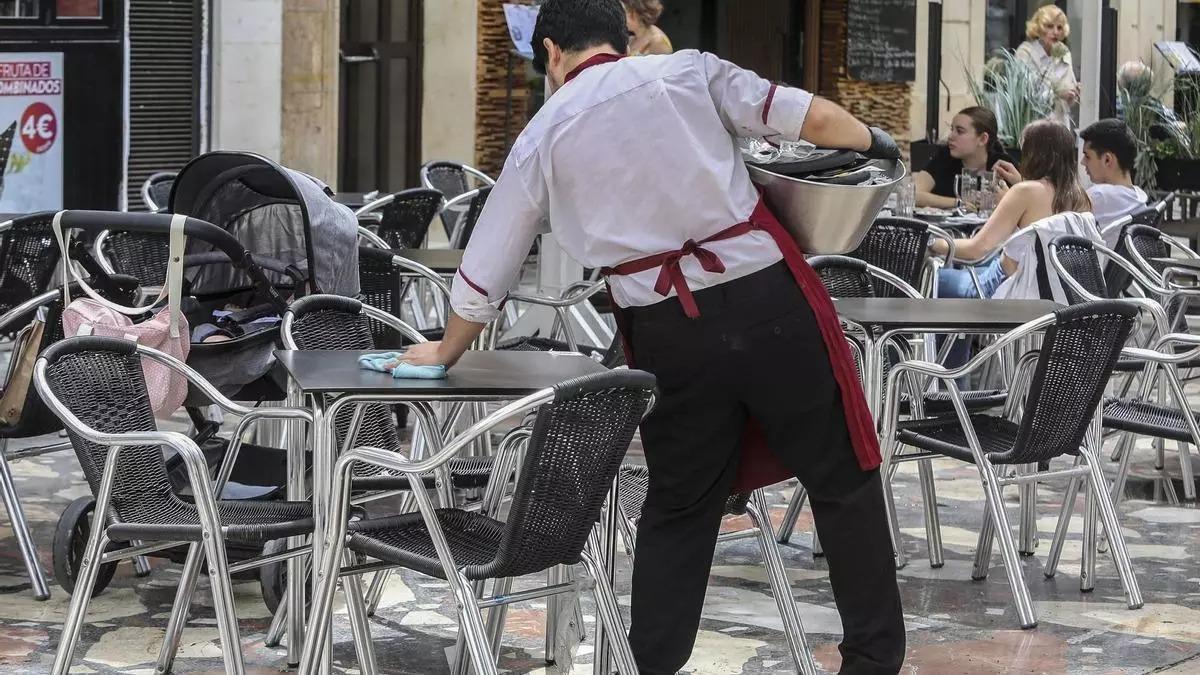 Un camarero limpia la mesa de una terraza en Zaragoza.