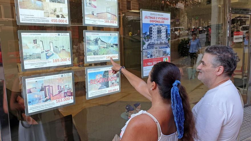 Una pareja ve anuncios de pisos en venta en una inmobiliaria de Vigo.