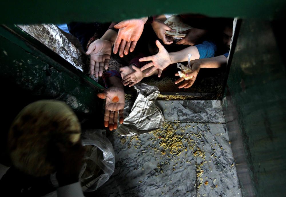 Mujeres y niños tratan de alcanzar comida en un centro de distribución de alimento gratuito en Islamabad, Pakistán.