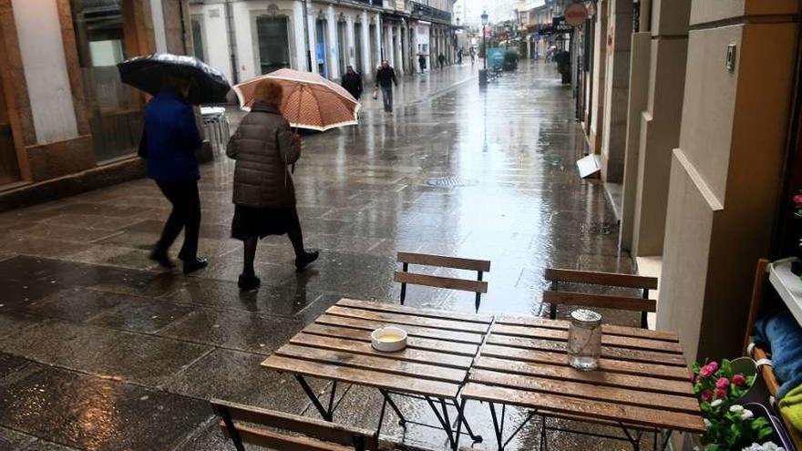 Dos personas se protegen de la lluvia en una calle de A Coruña.