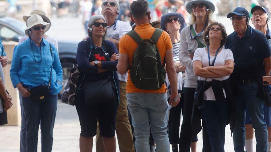Un grupo de turistas atiende las explicaciones de un guía en las Torres de Serranos. | FERNANDO BUSTAMANTE