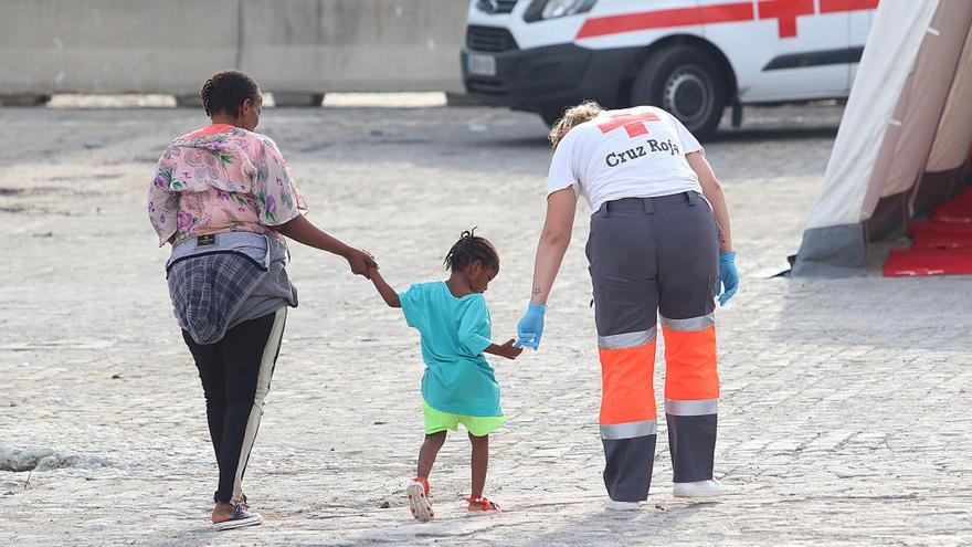 Un voluntario de Cruz Roja ayuda a una de las mujeres y a una menor llegadas en patera.