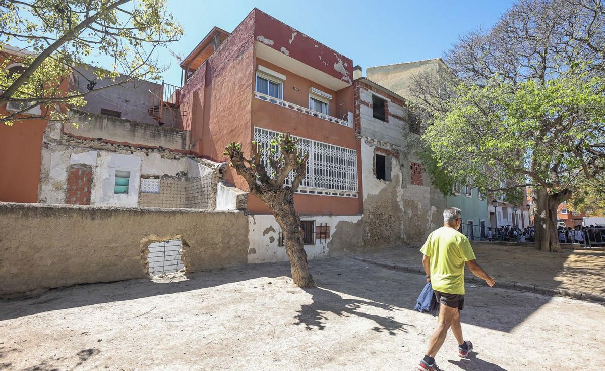 Un hombre camina frente a varios edificios residenciales de Santa  Faz, con aspecto de abandono en sus muros, a principios de semana. | HÉCTOR FUENTES