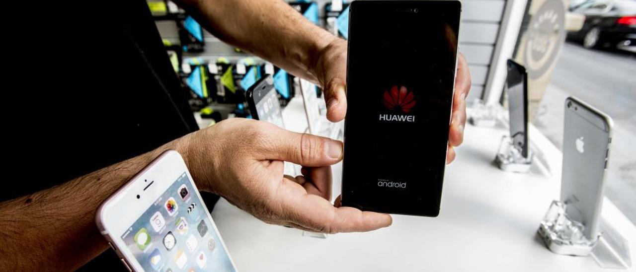 El empleado de un comercio de telefonía muestra una de las terminales de Huawei que vende.