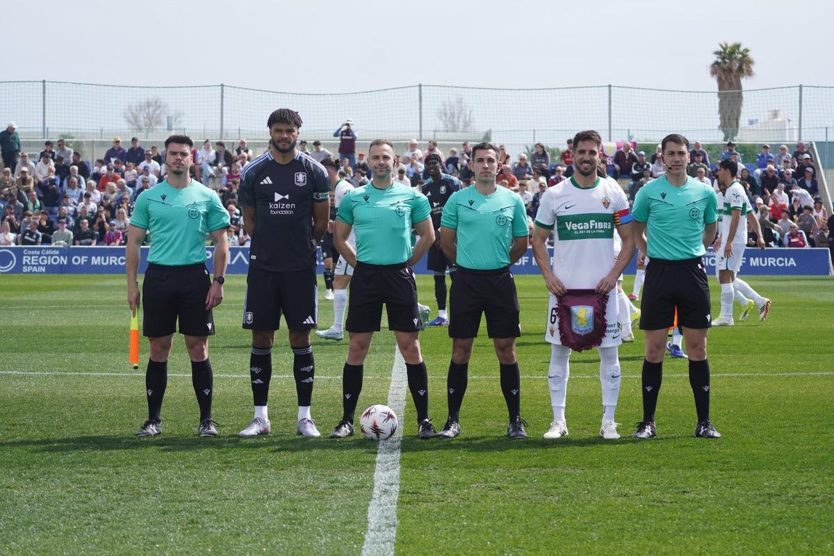 Tyrone Mings y Pedro Bigas, capitanes de ambos equipos, posan con los árbitros antes del encuentro.