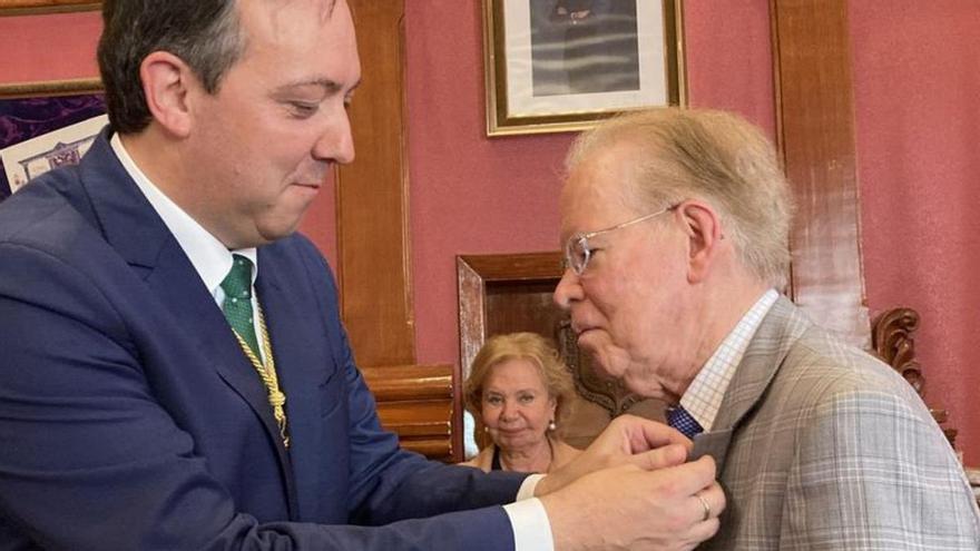 Alejandro Vega, alcalde de Villaviciosa, a la izquierda, pone la insignia de la ciudad a José Luis Corripio; al fondo, María Antonia Fernández Felgueroso, presidenta del Consejo de Comunidades Asturianas. | A. L.